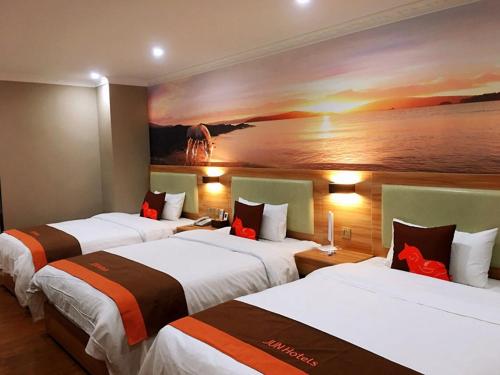 um quarto de hotel com três camas e um quadro na parede em JUN Hotels Chongqing Yubei District Jiangbei International Airport Airport Plaza em Yubei