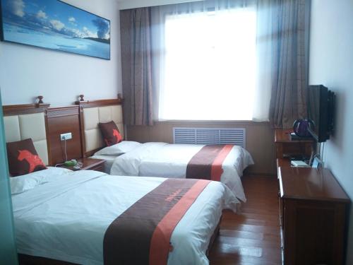 a hotel room with two beds and a window at JUN Hotels Yulin Yuyang District South Gate Bus Station in Yulin