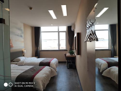 a hotel room with two beds and two windows at Thank Inn Chain Hotel Shandong Qingdao Huangdao West Coast Bus Station in Qingdao