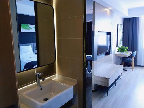 een badkamer met een wastafel, een spiegel en een bed bij Up And In Qingdao Jimo District Aoshanwei Blue Silicon Valley in Qingdao