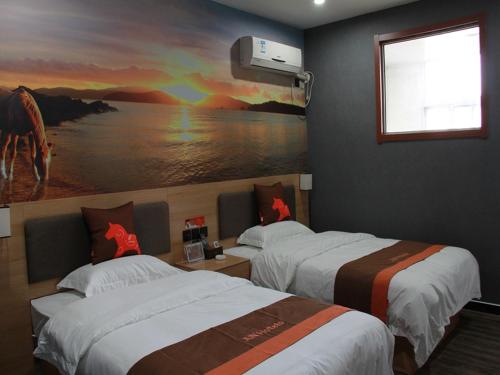 two beds in a room with a painting on the wall at JUN Hotels Laiwu Laicheng District Changshao North Road in Laiwu