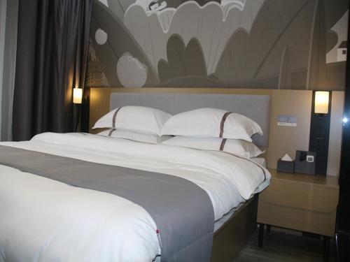 Quannan的住宿－尚客优酒店江西赣州全南县寿梅路店，卧室配有一张带白色床单和枕头的大床。