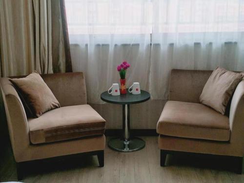 a living room with two chairs and a table with flowers at JUN Hotels He'nan Zhoukou Shenqiu Zhaofeng Avenue in Zhoukou