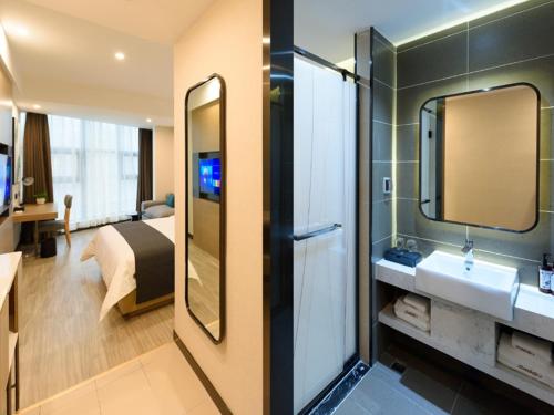 a bathroom with a sink and a bed and a mirror at Up And In Sichuan Mianyang Sena Sunshine High-speed Railway Station in Mianyang