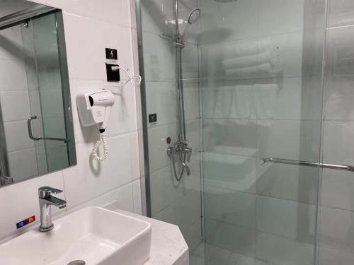 a bathroom with a shower with a sink and a glass shower door at JUN Hotels Suqian Muyang Baimeng Logistics Park in Suqian