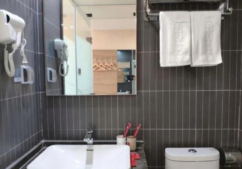 W łazience znajduje się umywalka, toaleta i lustro. w obiekcie Thank Inn Chain Hotel Shandong Qingdao Huangdao West Coast Bus Station w mieście Qingdao