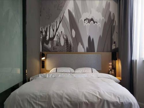 a bedroom with a large white bed with a painting on the wall at Thank Inn Chain Hotel Anhui Suzhou Lingbi County People's Hospital Zhongxiu Jincheng in Suzhou