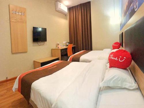a hotel room with two beds with a person sitting on them at JUN Hotels ujian Fuzhou Jinan District Railway Station in Fuzhou