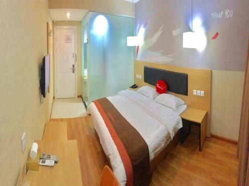 a bedroom with a large bed with a red pillow on it at JUN Hotels ujian Fuzhou Jinan District Railway Station in Fuzhou
