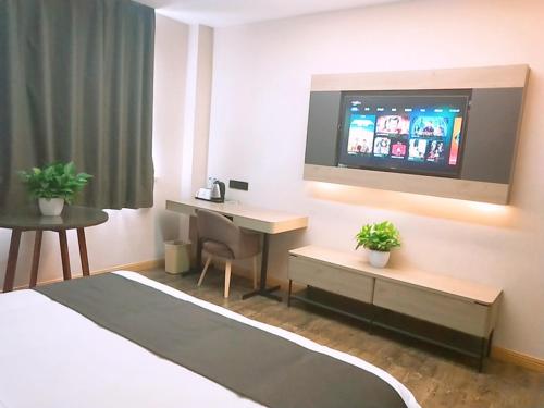 a hotel room with a desk and a television at Thank Inn Plus Hotel Jiangsu Suzhou Taicang Liuhe Town Tinghai Road in Taicang