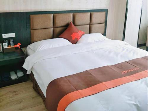 um quarto com uma cama grande e uma grande cabeceira. em JUN Hotels He'nan Zhoukou Shenqiu Zhaofeng Avenue em Zhoukou