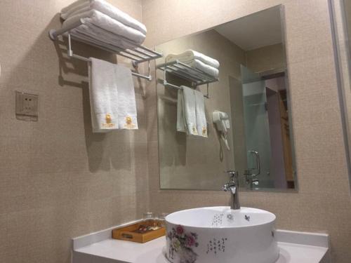 ein Badezimmer mit einem Waschbecken, einem Spiegel und Handtüchern in der Unterkunft JUN Hotels Henan Luoyang Xigong District Central Bus Station in Luoyang