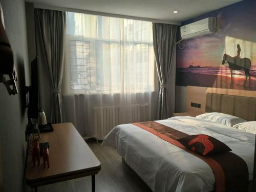 a bedroom with a bed with a painting on the wall at JUN Hotels Hebei Hengshui Taocheng Railway Station Square West Side in Hengshui