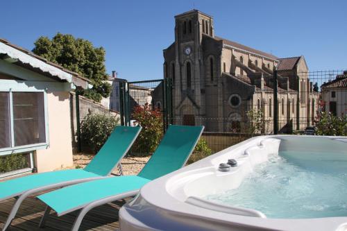 un bain à remous avec des chaises longues et une église dans l'établissement La Maison DUFFOUR chambres d'hôtes avec Petit Déjeuner, à Tonneins