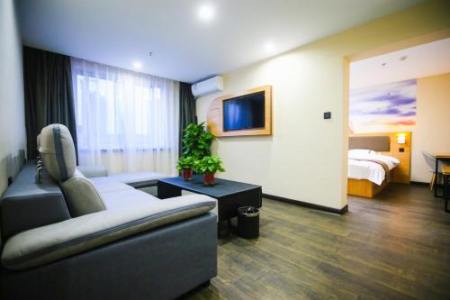 um quarto de hotel com um sofá e uma cama em Thank Inn Chain Hotel Panjin Shuangtaizi District Railway Station em Panjin