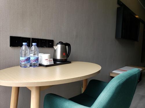 una mesa con 2 botellas de agua y 2 sillas en Thank Inn Chain Hotel Anhui Anqing Yixiu District Government University Town, en Anqing