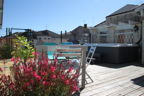 a chair and a table on a deck with pink flowers at La Maison DUFFOUR chambres d'hôtes avec Petit Déjeuner in Tonneins