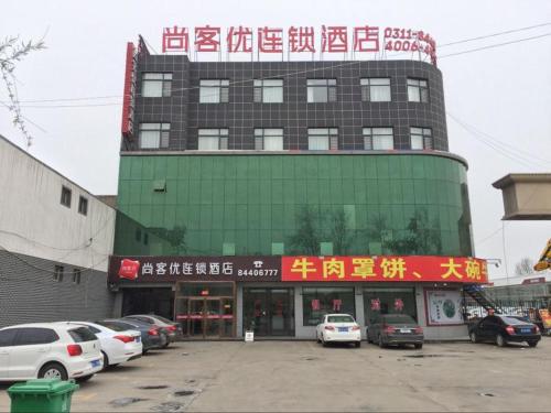 石家荘市にあるThank Inn Chain Hotel Hebei Shijiazhuang Jinzhou New Times Auto Plazaの駐車場車を停めた大きな建物