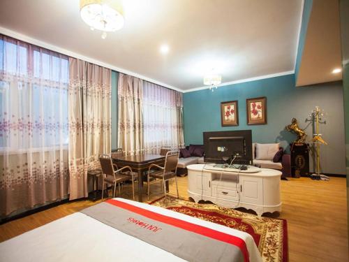 a bedroom with a bed and a living room at JUN Hotels Hebei Xingtai Qiaodong District South Xinhua Road in Xingtai