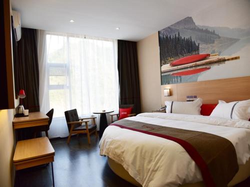 a hotel room with a large bed and a desk at Thank Inn Chain Hotel Guizhou Tongren Bijiang District High-speed Railway Station Qingshui Avenue Store in Tongren