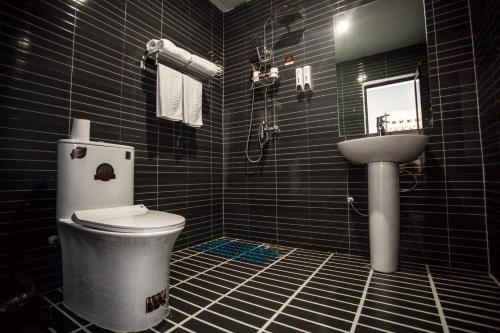 a black tiled bathroom with a toilet and a sink at JUN Hotels Hebei Xingtai Qinghe County Bohai Road in Huangjinzhuang