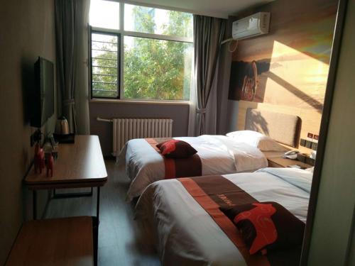 a hotel room with two beds and a desk and a window at JUN Hotels Hebei Hengshui Taocheng Railway Station Square West Side in Hengshui