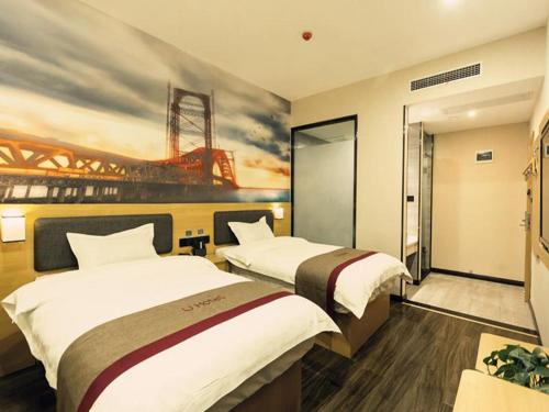 two beds in a hotel room with a painting on the wall at Thank Inn Chain Hotel Xi'an Weiyang District High Speed Rail North Passenger Station in Xi'an