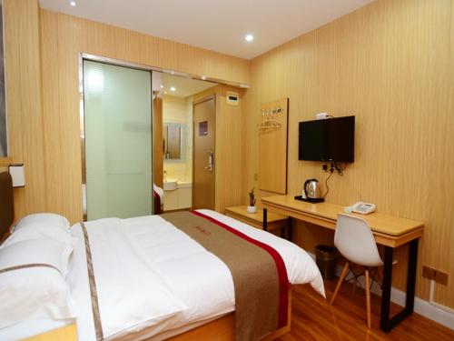 a bedroom with a bed and a desk and a television at Thank Inn Chain Hotel Jiangxi Fuzhou Dongxiang District High Speed ââRailway Station in Fuzhou
