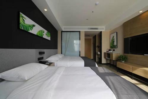 a hotel room with two beds and a flat screen tv at Up And In Anhui Huainan Tianjiaan District Hualian Commercial Building in Huainan