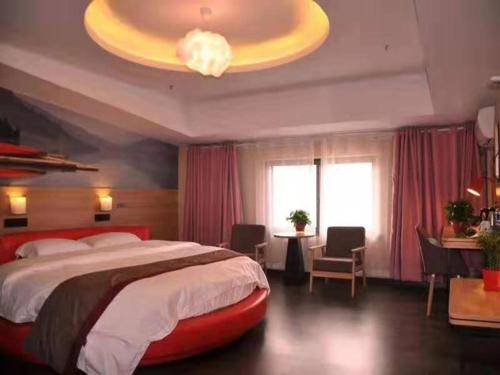 1 dormitorio con cama grande y lámpara de araña grande en Thank Inn Chain Hotel Anhui Fuyang Trade City Store, en Fuyang