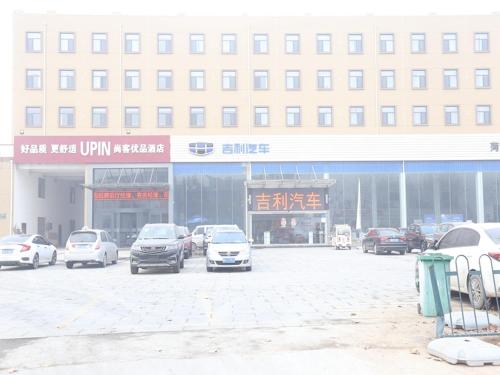 un estacionamiento con autos estacionados frente a un edificio en Up and In Heze Development zone Huanghe Road, en Heze