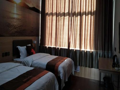 a hotel room with two beds and a window at JUN Hotels Shandong Binzhou Yangxin County Yangcheng 3rd Road in Binzhou