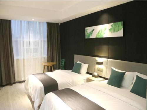 a hotel room with two beds with green accents at Up And In Shandong Linyi Lanshan District Taisheng Square in Linyi