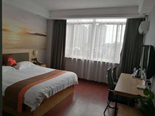 a bedroom with a bed and a desk and a window at JUN Hotels Zhejiang Jiaxing Haiyan Qiyuan North Road in Jiaxing