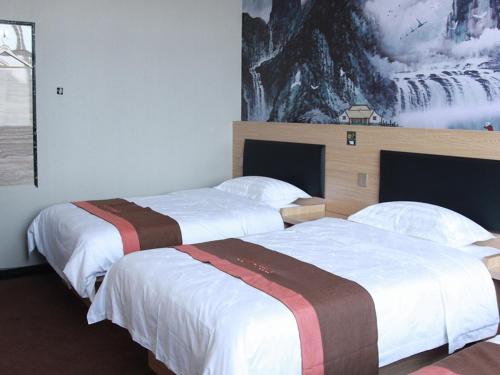 two beds in a hotel room with a painting on the wall at JUN Hotels Hebei Langfang Guangyang Langfang Station in Langfang