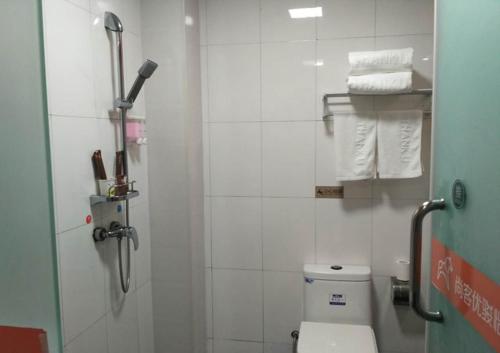 a bathroom with a shower with a toilet and towels at JUN Hotels Anyang Beiguan District Railway Station in Anyang