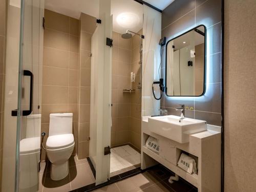 a bathroom with a toilet and a sink and a mirror at Up And In Henan Anyang Hongqi Road Wal-Mart in Anyang