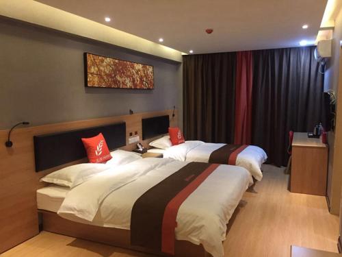 a hotel room with two beds with red pillows at JUN Hotels Dezhou Decheng District Xinhu Park Pedestrian Street in Dezhou