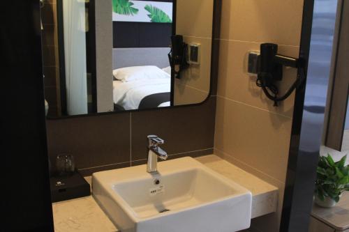 a bathroom with a sink and a mirror and a bed at Up And In Anhui Huainan Tianjiaan District Hualian Commercial Building in Huainan