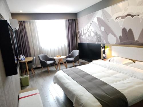 a hotel room with a large bed and chairs at Thank Inn Chain Hotel Anhui Anqing Yixiu District Government University Town in Anqing