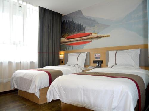 ein Hotelzimmer mit 2 Betten und einem Gemälde an der Wand in der Unterkunft Thank Inn Chain Hotel Aksu Juche Tianwu Plaza in Kuqa
