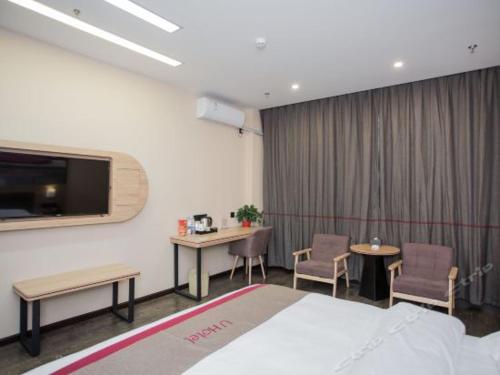 pokój hotelowy z łóżkiem oraz 2 stołami i krzesłami w obiekcie Thank Inn Plus Hotel Kunshan Wulian Commercial Center w mieście Suzhou