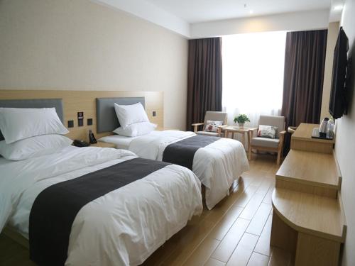 a hotel room with two beds and a television at Up and In Heze Development zone Huanghe Road in Heze