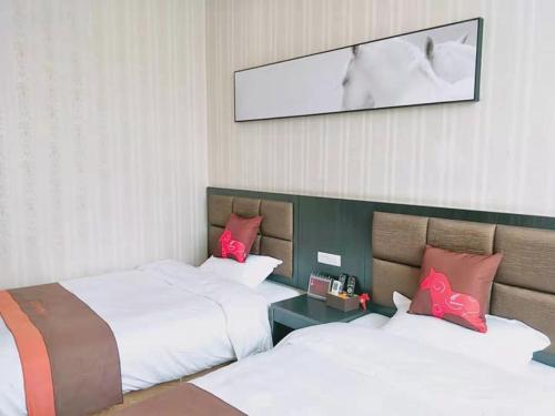 um quarto de hotel com duas camas com almofadas cor-de-rosa em JUN Hotels He'nan Zhoukou Shenqiu Zhaofeng Avenue em Zhoukou