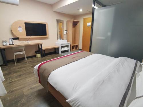 Dormitorio con cama, escritorio y TV en Thank Inn Chain Hotel Hohhot Xincheng District Xinhua Plaza, en Hohhot