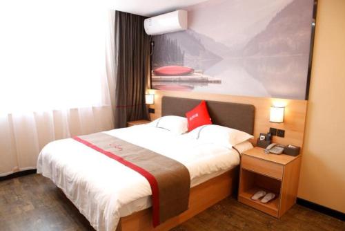 una habitación de hotel con una cama grande y una pintura en Thank Inn Chain Hotel Shandong Linyi Lanshan District Liguan Town, en Linyi