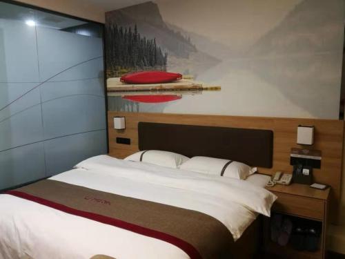 a bedroom with a large bed and a painting on the wall at Thank Inn Chain Hotel Anhui Lu'an Shucheng Yuanda Ganghui in Lu'an