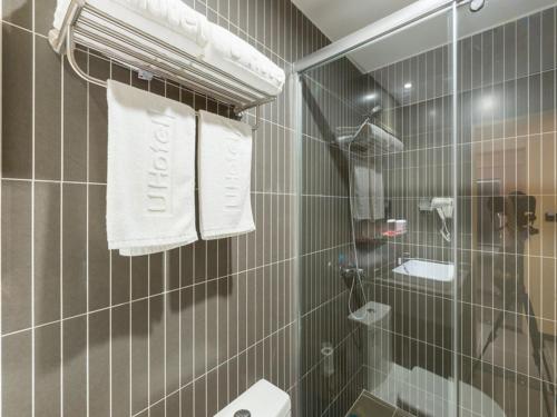 uma casa de banho com uma cabina de duche em vidro e toalhas em Thank Inn Chain Hotel Shanghai Songjiang District Yongfeng Road Store em Xangai