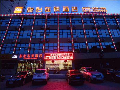 a building with cars parked in front of it at JUN Hotels Zhangjiakou Qiaodong District Yu'er Mountain Taihe Home in Zhangjiakou