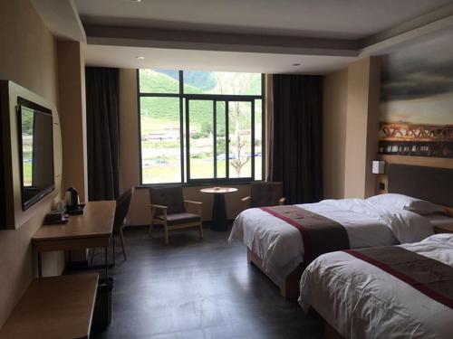 GarzeにあるThank Inn Chain Hotel Ganzi Kangding City Xinduqiaoのベッド2台、デスク、窓が備わるホテルルームです。